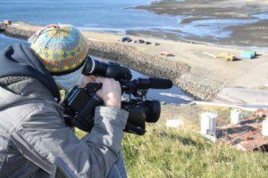 Man with hat filming from a hill