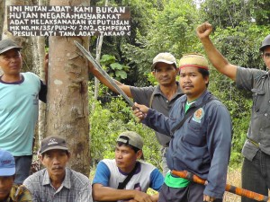 Picture Caption: Pak Masrani, village head of Muara Tae, points to a sign declaring the community's customary rights over the forests
