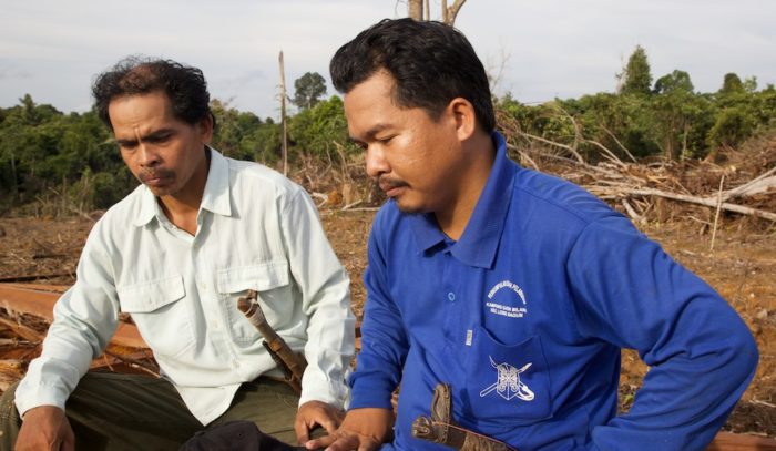 Muara Tae residents Petrus Asuy (left) and Masrani Tran sit in territory claimed by both their village and neighboring Muara Ponak, which struck a deal with First Resources to develop an oil palm plantation in the area. Photo: EIA