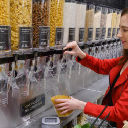 A shopper in Waitrose filling a reusable container with pasta